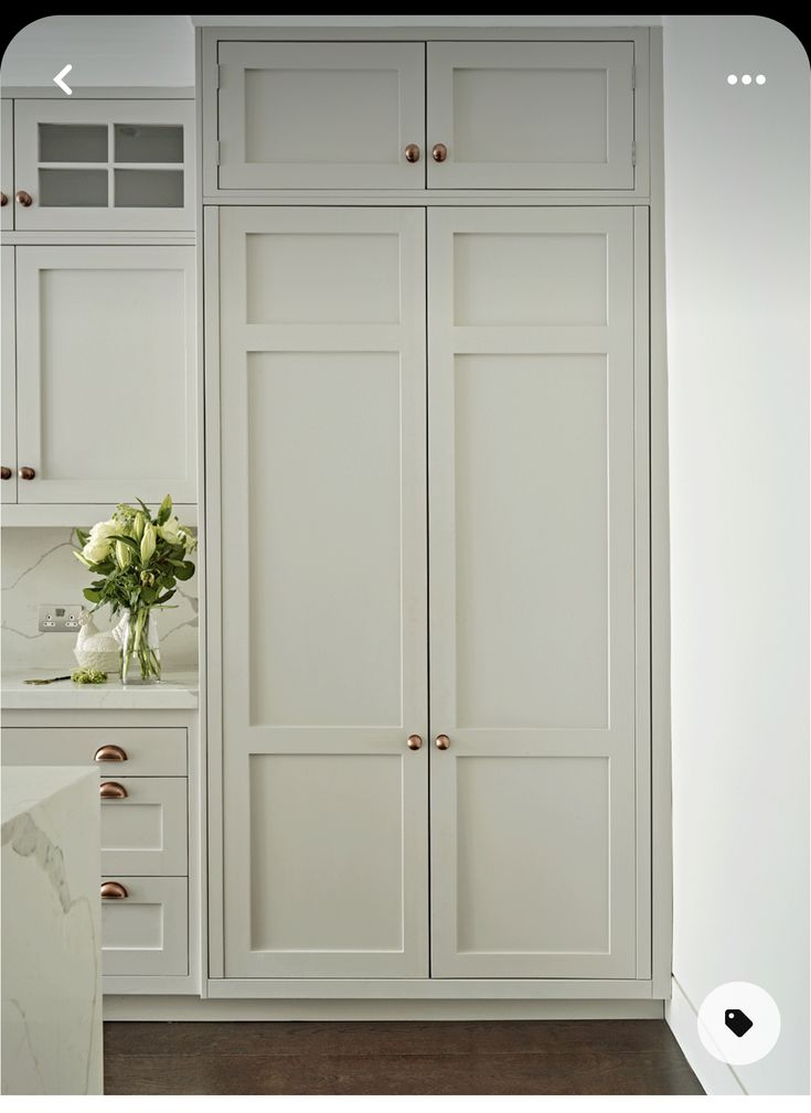 a kitchen with white cabinets and marble counter tops