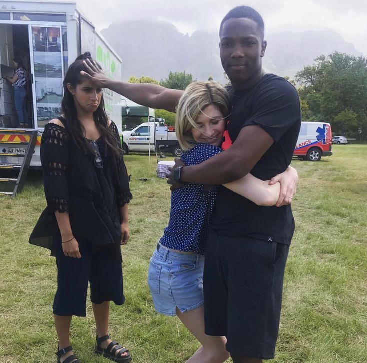 two women and a man standing in front of a camper with their arms around each other