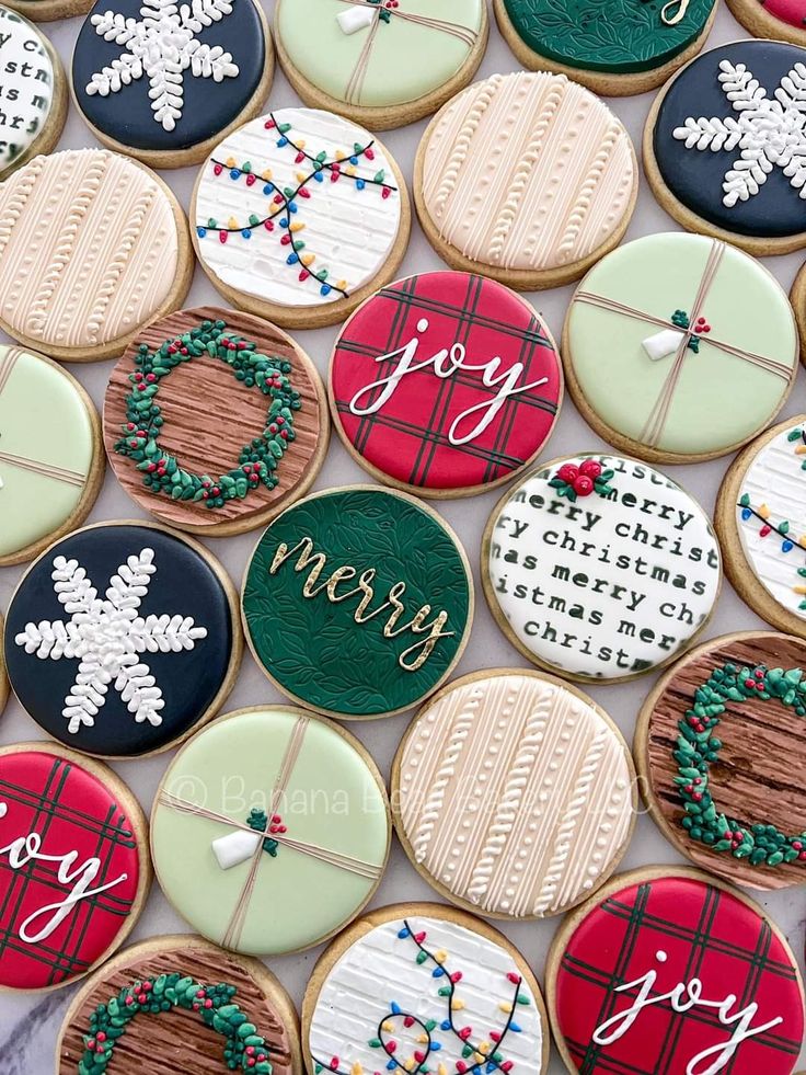 decorated cookies are arranged in rows on a sheet of paper with the words joy, merry and snowflakes