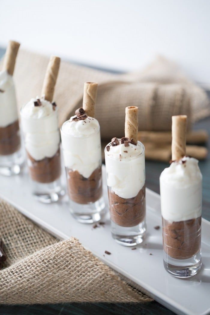 small desserts are lined up on a white tray with chocolate and marshmallows