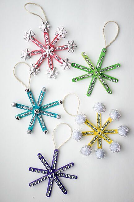 four snowflake ornaments are hanging on a white surface with string attached to them