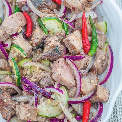 a white bowl filled with meat and veggies