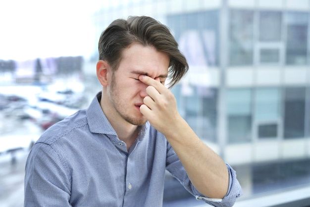 a man sitting in front of a window holding his hand to his face