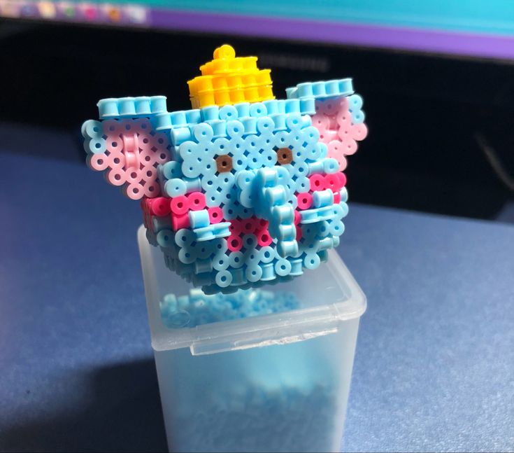 a plastic container filled with beads on top of a blue table next to a computer monitor