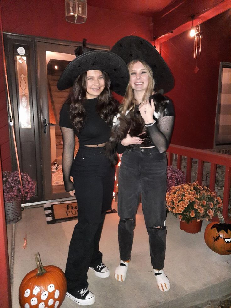 two young women dressed in halloween costumes standing on the porch with pumpkins behind them