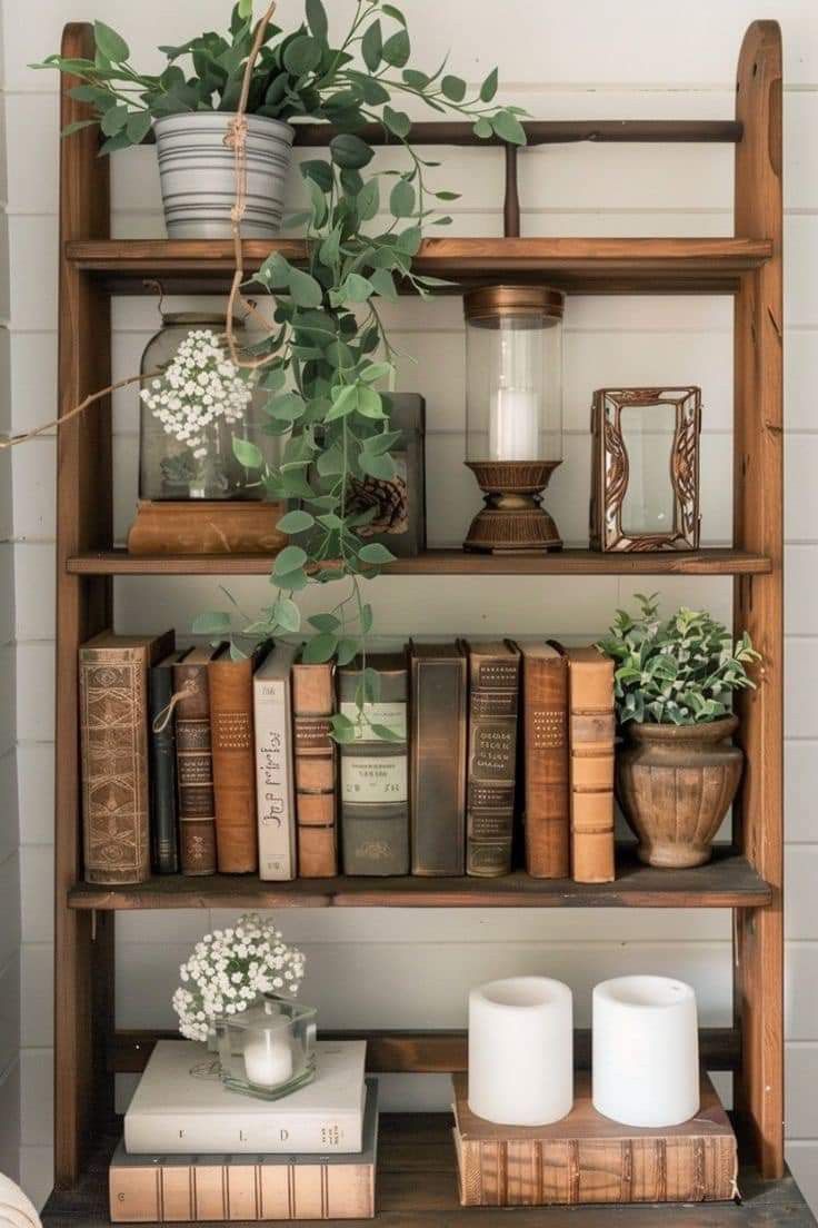 a shelf with books, candles and plants on it