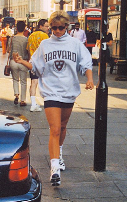 a woman is walking down the street with her foot in the air while wearing shorts and a sweatshirt