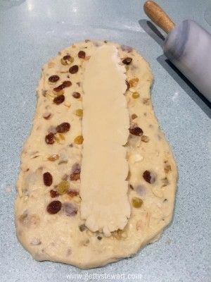 an uncooked dough with raisins and cheese on it next to a rolling pin