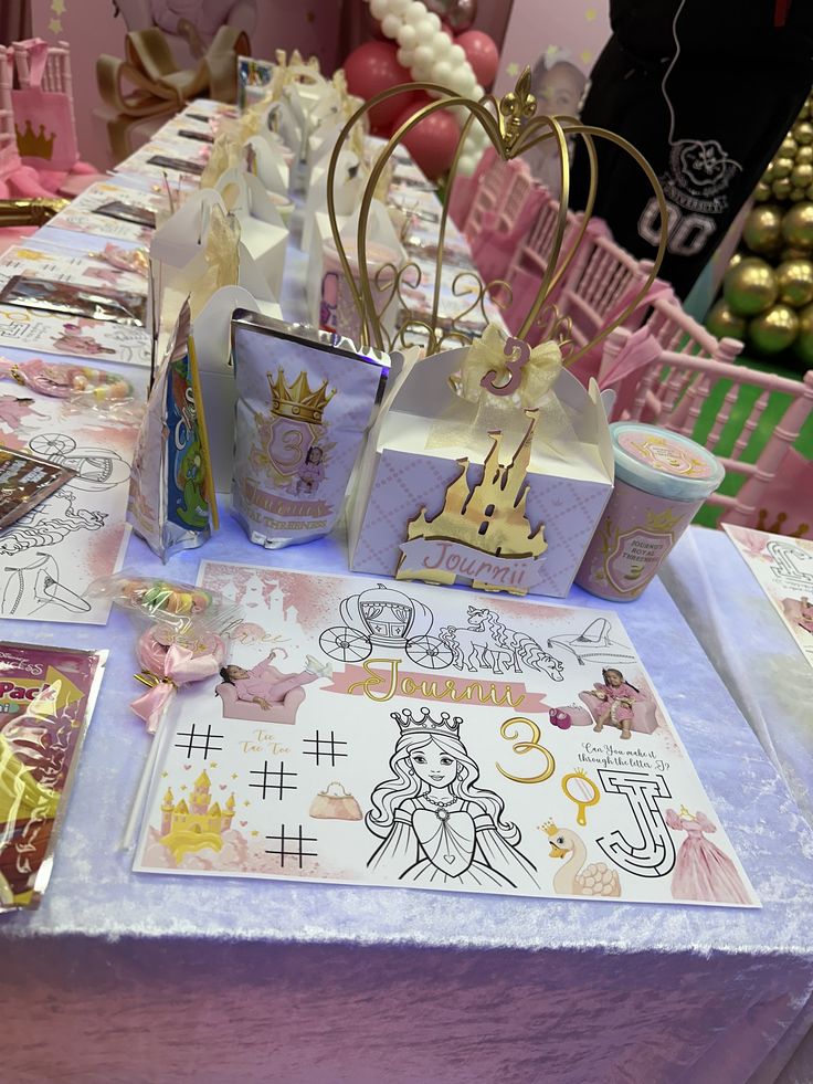 the table is set up with princess themed items and decorations, including paper bags for favors