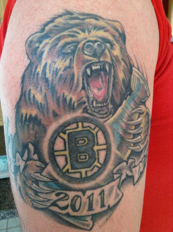 a man with a bear tattoo on his arm and chest is holding a hockey puck