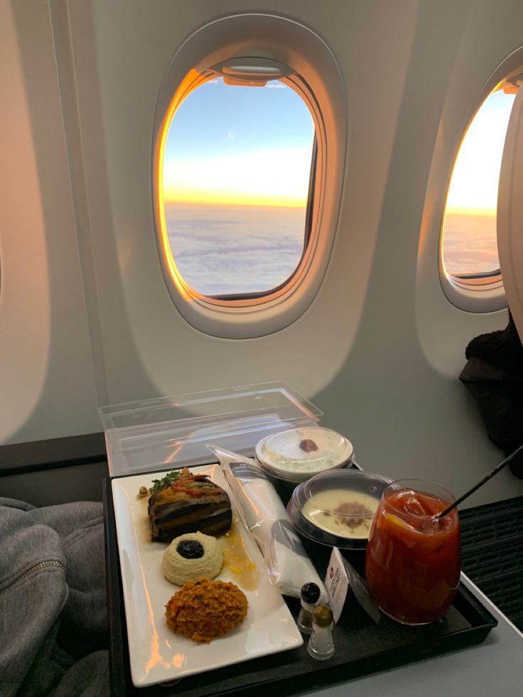 an airplane tray with food and drinks on it in front of two windows overlooking the ocean