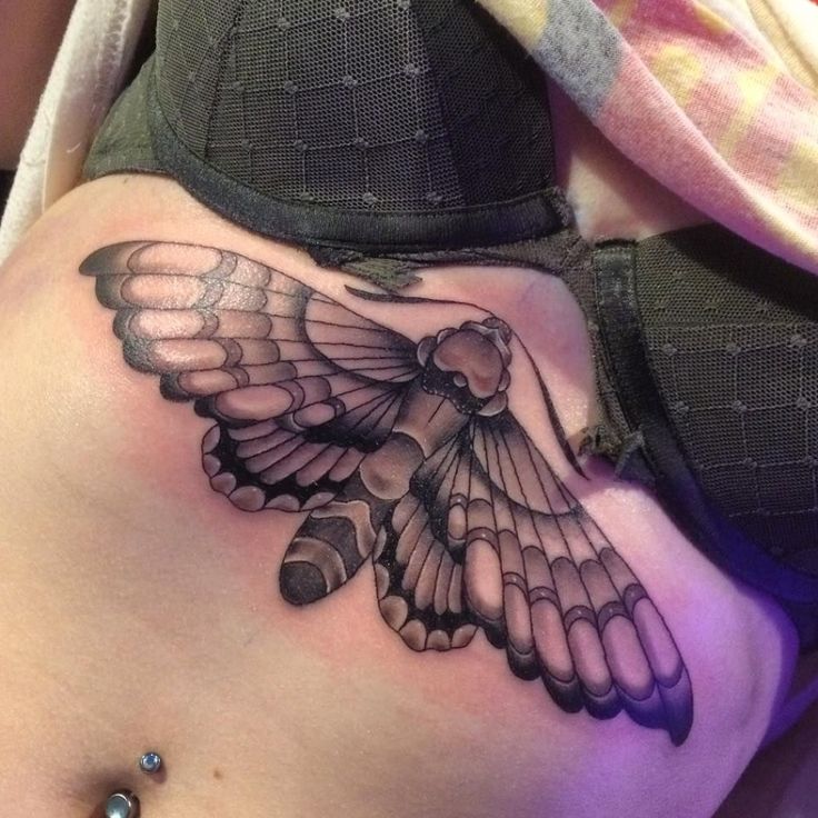 a woman's stomach with a tattoo of a bird on the side and wings