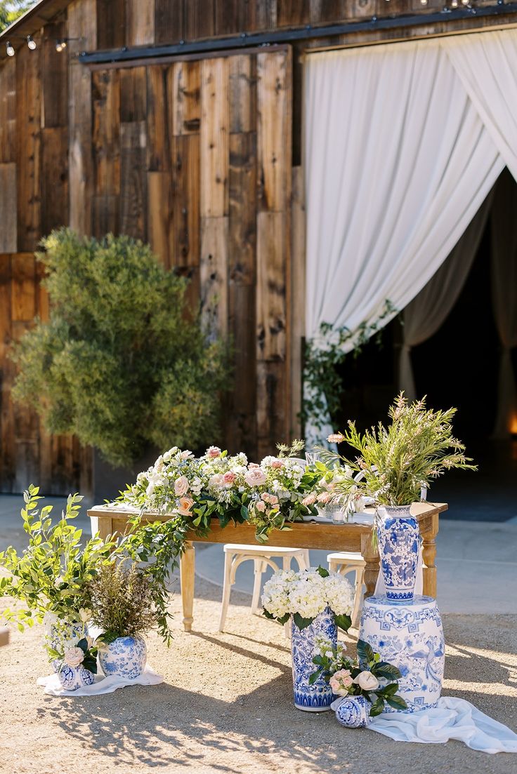 blue and white vases on display in front of an old barn with drapes