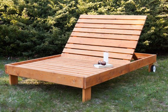 a wooden bench sitting on top of a grass covered field next to bushes and trees