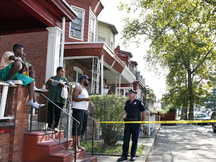 police officers standing on the sidewalk in front of a house with tape taped to it