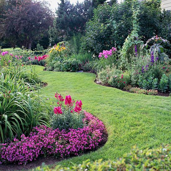 the garden is full of colorful flowers and greenery, along with lush green grass