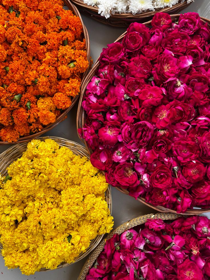 baskets filled with different colored flowers sitting on top of a white table next to each other