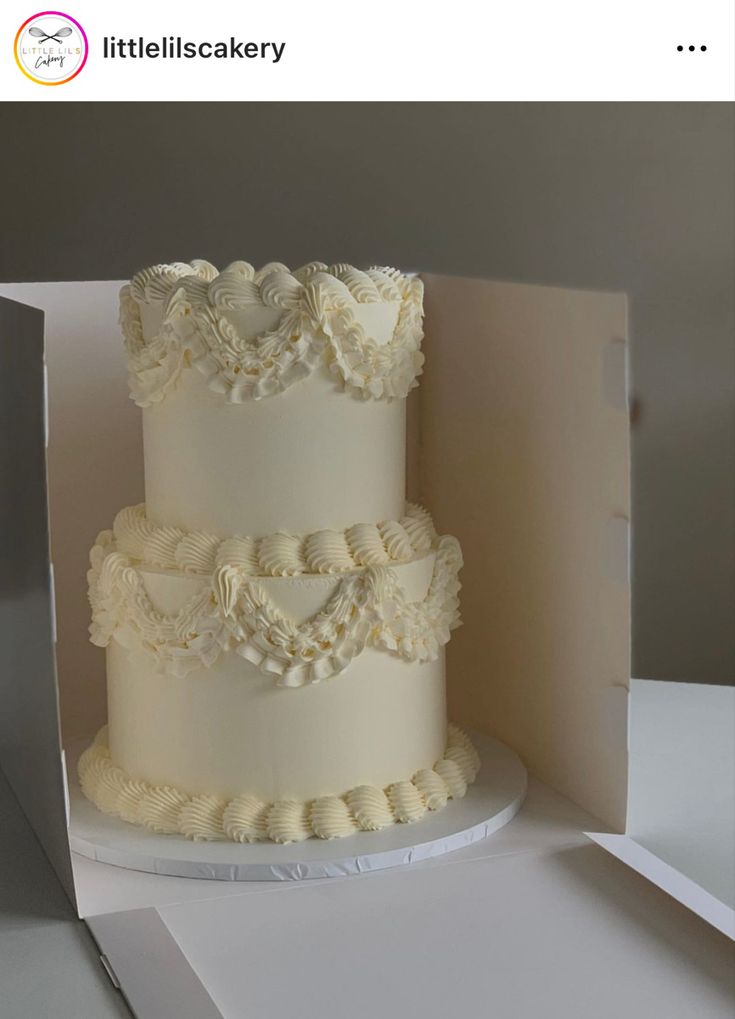 a three tiered wedding cake sitting on top of a white tablecloth covered box