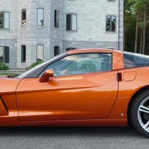 an orange sports car parked in front of a large building