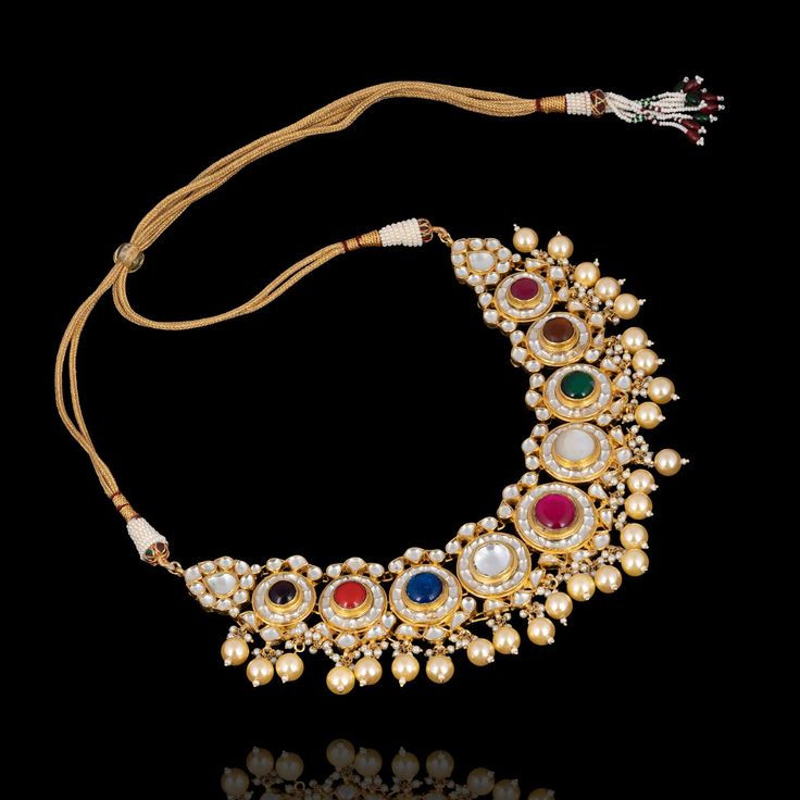 Celebrate your big day by adorning this nauratan regalia - a classic combination of exquisite and sophistication! Strike a regal bridal look with an elegant set exuding an unparalleled blend of nauratan and kundan stones enriched with pearl moti embellishments to redefine tradition. The set includes a necklace, a maang teekah and a pair of jhumki earrings. Approximate earring length is 2.25". Gold-plated on high-quality brass as the base metal. Made by order. Kindly allow 5-7 weeks for the deliv Elegant Kundan Necklace For Designer Wear, Kundan Pearl Necklace With Stone Work For Reception, Traditional Designer Jewelry With Zari Work, Elegant Multicolor Kundan Lehenga, Designer Kundan Bridal Necklace With Intricate Design, Kundan Pearl Necklace With Meenakari For Reception, Reception Kundan Temple Necklace With Stone Work, Gold Kundan Necklace With Zari Work For Designer Wear, Ceremonial Kundan Pearl Necklace With Stone Work