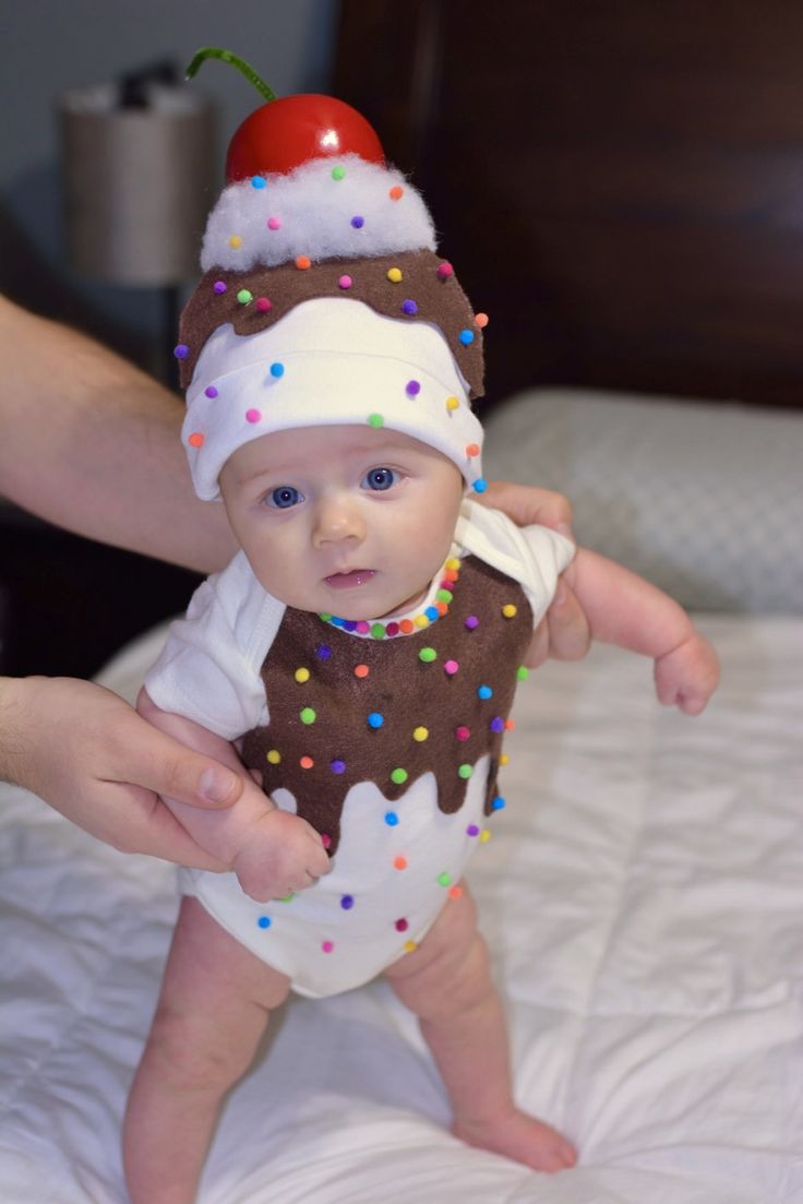 a baby wearing a chocolate donut with sprinkles and a cherry on top