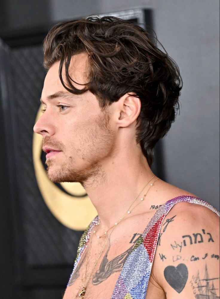 a close up of a person with tattoos on his chest and shoulder, looking to the side