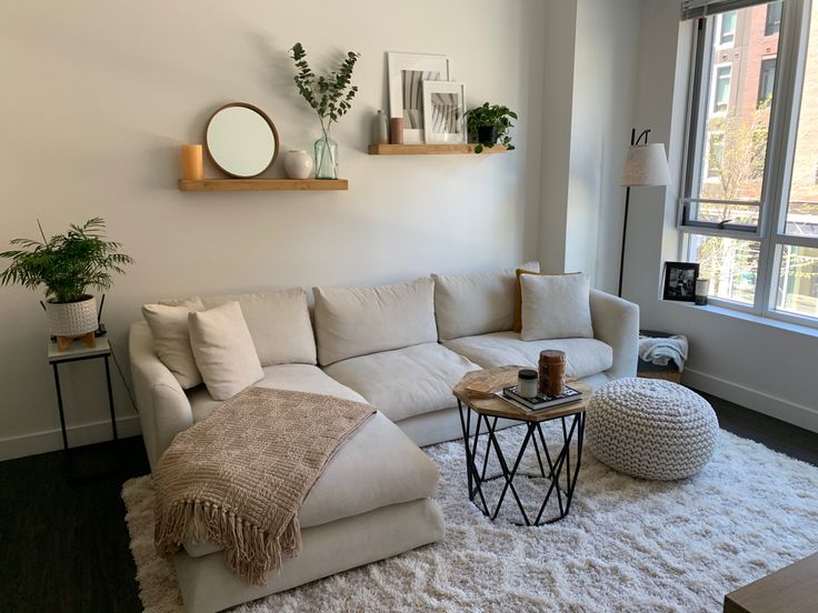 a living room filled with furniture next to a window and a white rug on the floor