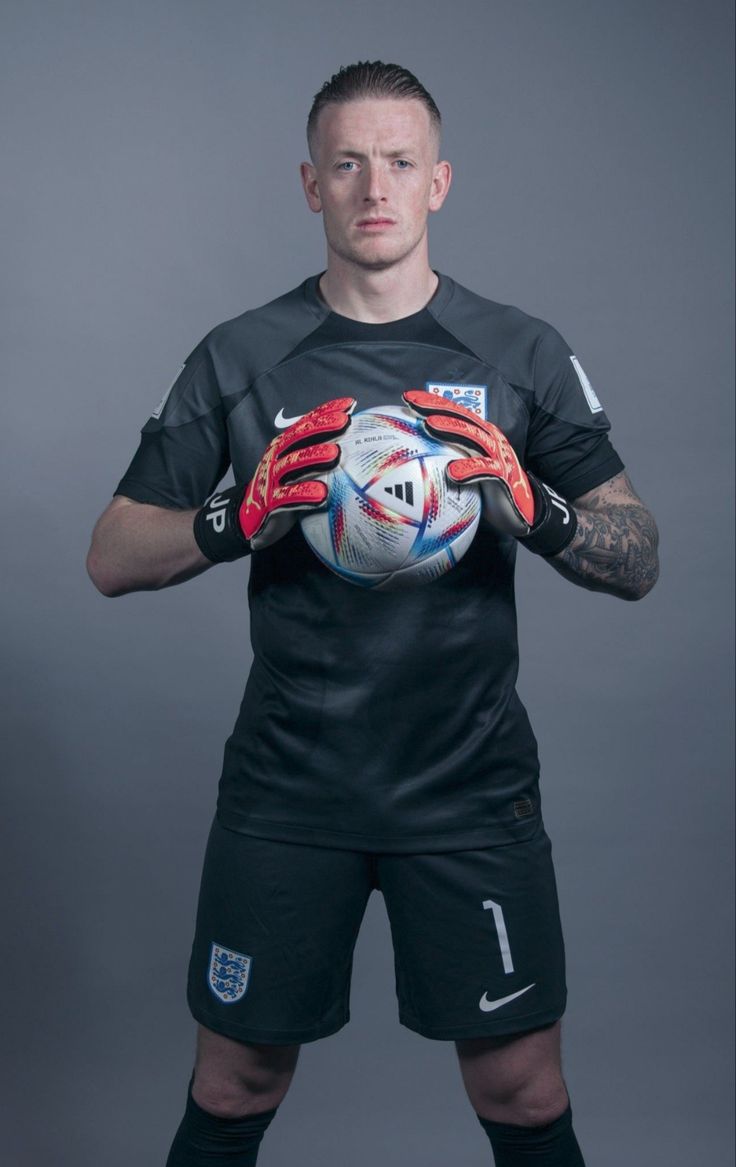 a man holding a soccer ball in his hands and wearing gloves with the number 1 on it