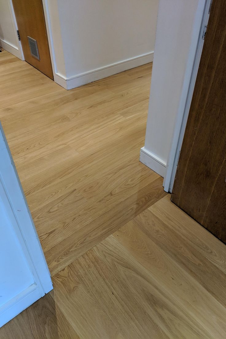 an empty room with hard wood floors and white trim on the door, is seen in this image