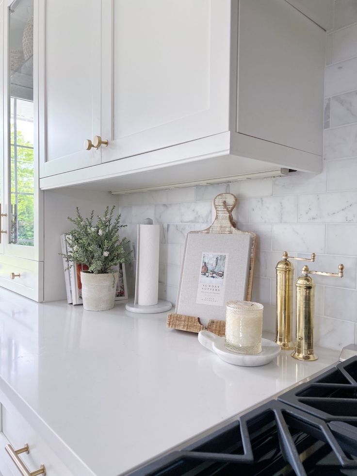 a white kitchen counter with gold accents and candles on the stove top next to it