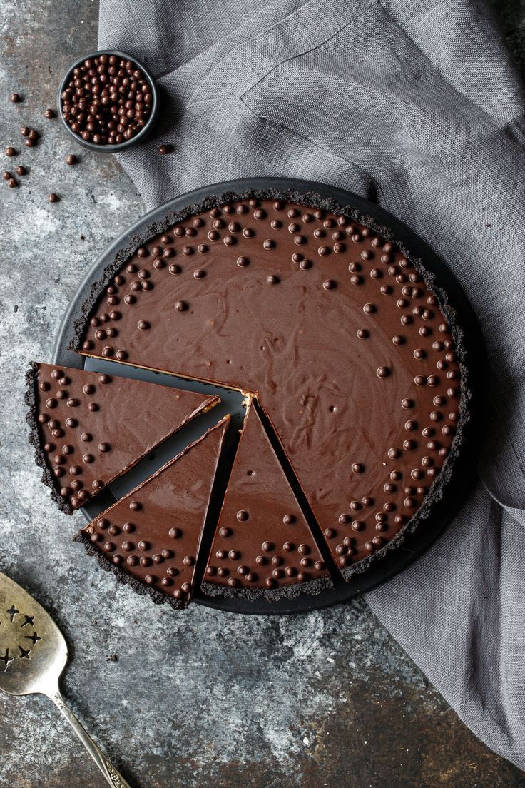 a chocolate cake with three slices missing from it on a plate next to a spoon