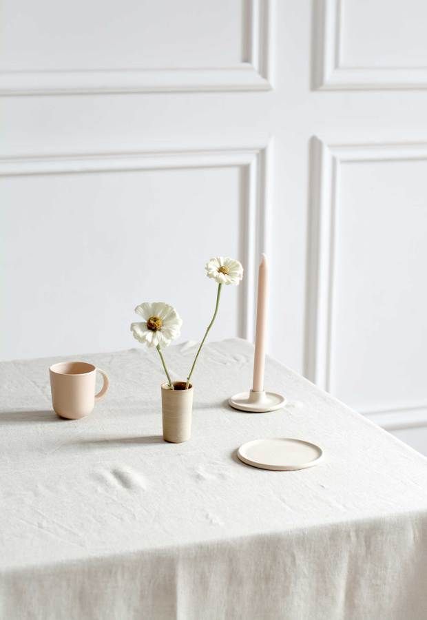 a table topped with two vases filled with flowers next to candlesticks and plates