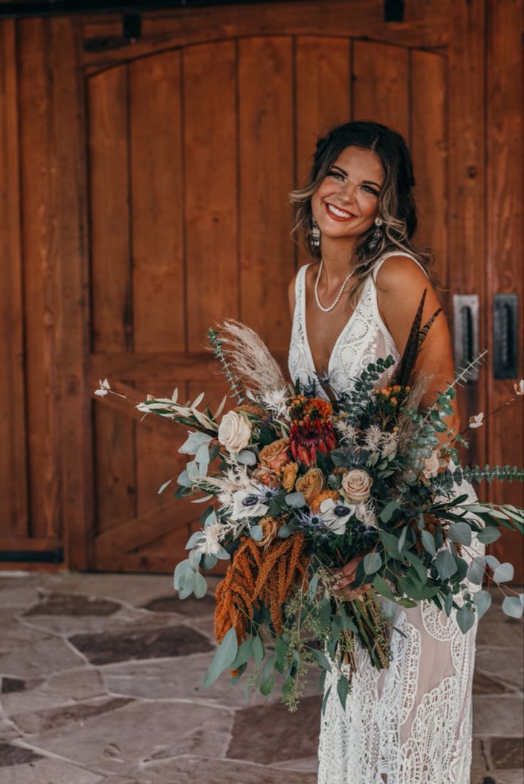 a woman holding a bouquet in front of a wooden door