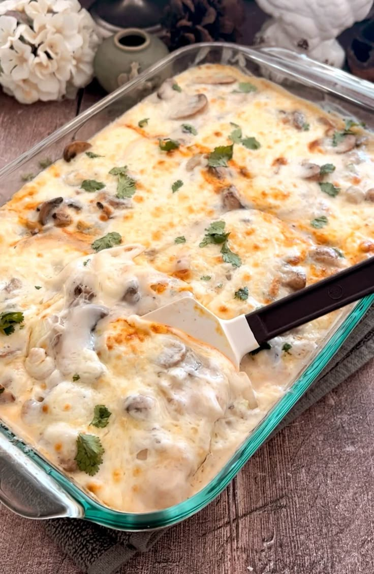 a casserole dish with cheese, mushrooms and broccoli in it on a wooden table