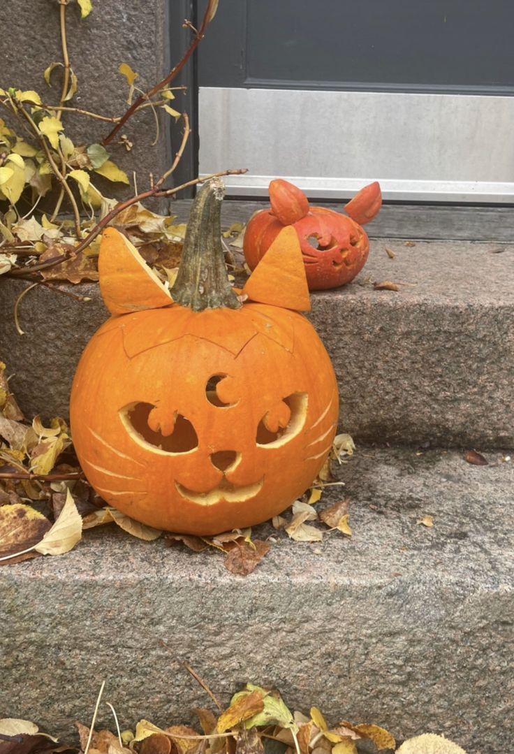 two pumpkins with faces carved into them sitting on the steps