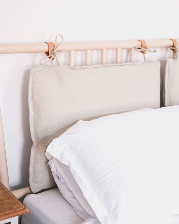 an unmade bed with white sheets and pillows on top of it next to a night stand