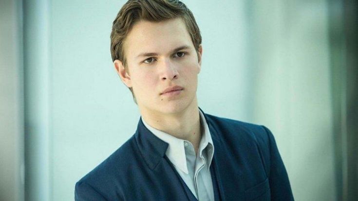 a young man in a blue jacket and white shirt looking at the camera with an intense look on his face