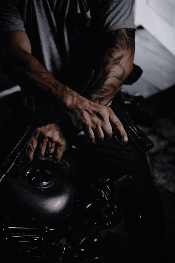 a man sitting on top of a motorcycle with his hands resting on the handlebars