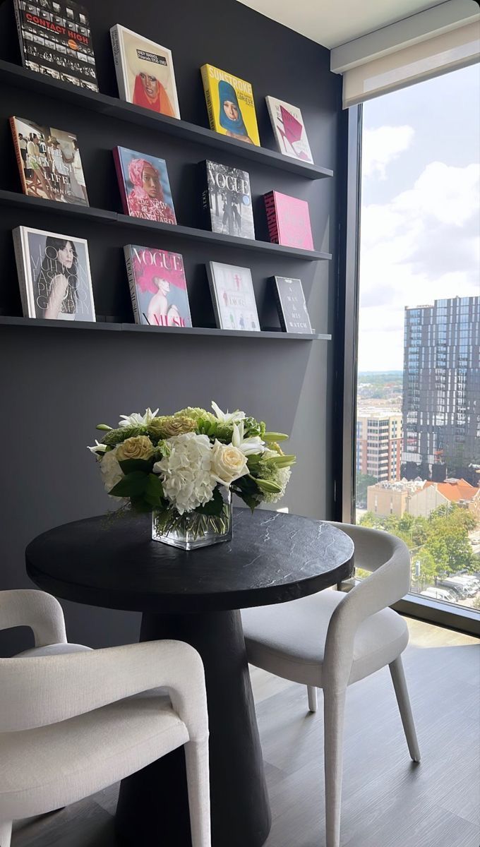 there is a vase with flowers on the table in front of some bookshelves