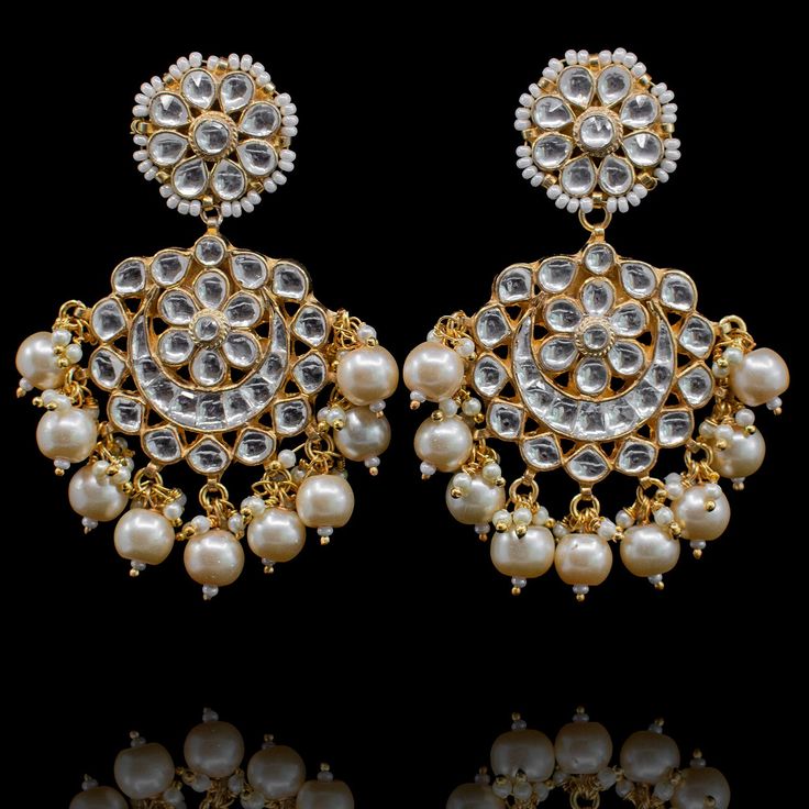 The best handcrafted jewels for every beautiful bride! The look includes necklace, earrings, maang teekah, jhoomar, pair of haathphool and nose ring. The stunning set incorporates age old Mughal techniques of kundan work, metal detailing and pearl adornments complemented with a matching maang teekah and a pair of beautiful earrings. The majestic jhoomar is adorned with lush kundan and pearl beads together with an elegant and classic pair of haathphool encrusted with kundan stones in a floral fra Hand Set Kundan Bridal Earrings For Wedding, Kundan Bridal Earrings For Wedding, Temple Style Chandbalis With Stone Work For Reception, Hand Set Kundan Bridal Earrings For Reception, Kundan Tilla Bridal Earrings For Wedding, Gota Work Bridal Earrings For Reception And Festivals, Ceremonial Kundan Bridal Earrings In Temple Style, Kundan Danglers With Stone Work For Reception, Silver Kundan Chandelier Earrings For Wedding