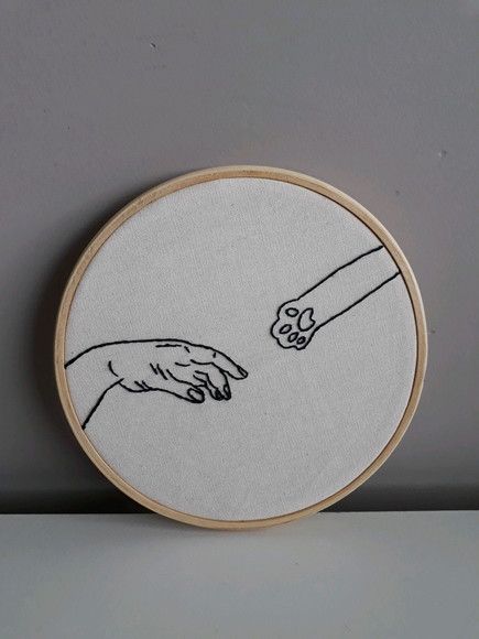 two hands are touching each other with one hand embroideryed onto the back of a hoop