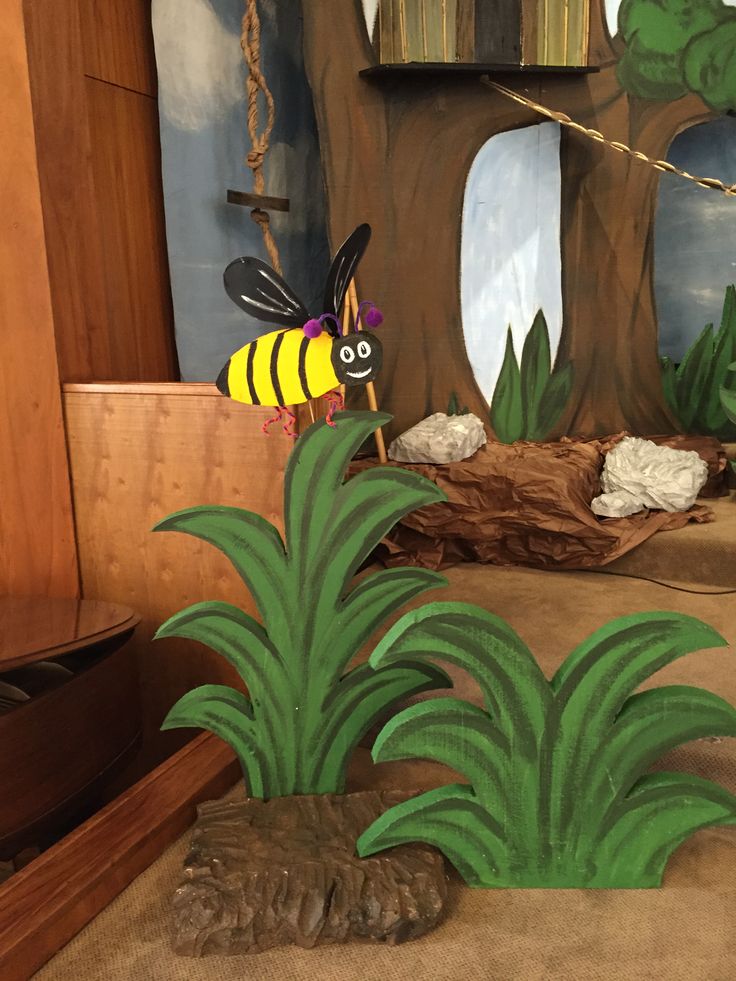 a paper cut out of a bee sitting on top of a plant in front of a tree