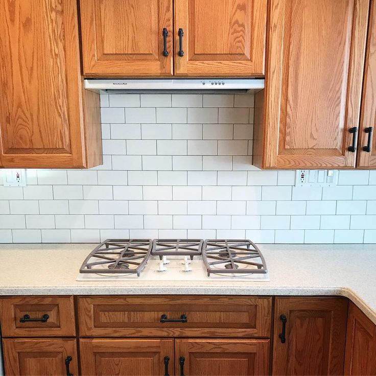 a stove top oven sitting inside of a kitchen next to wooden cupboards and cabinets