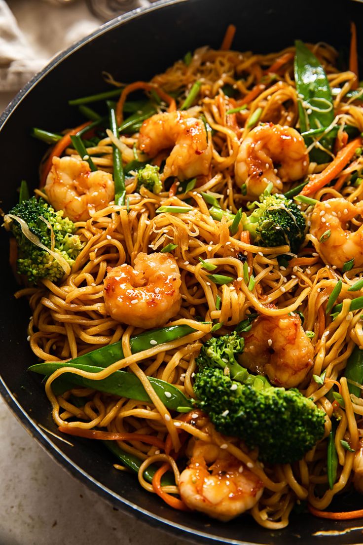 a skillet filled with shrimp, broccoli and noodles