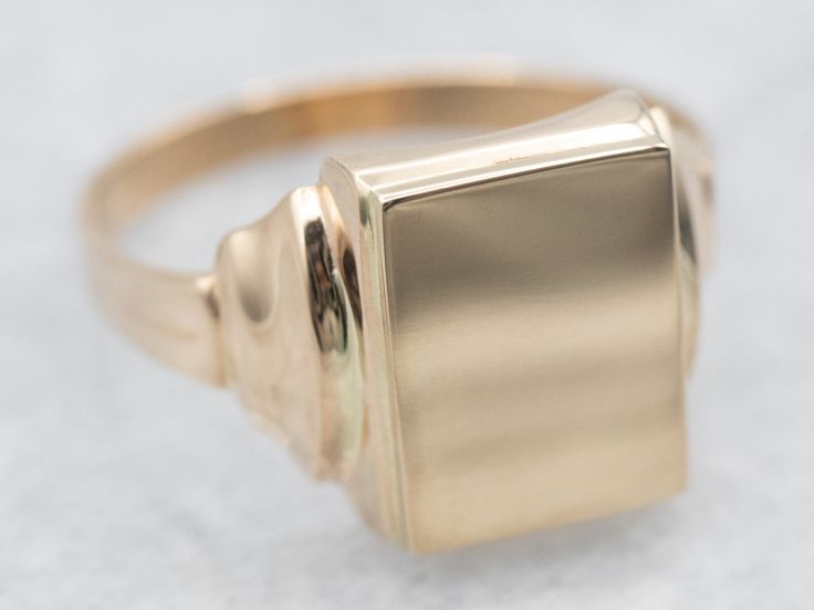 This signet ring is crafted from yellow gold and is the perfect way to make a statement. The timeless rectangular shape and simple design make this an ideal accessory for any style.Market Square Jewelers works with one of the finest hand engravers in the northeast. With over 30 years of experience, our engraver hand carves lettering, monograms, crests, or patterns in period-specific styles. Choose from our many monogram options shown in the listing or contact us directly with your own crest, or monogram, or for additional information, and pricing!Metal: 14K Yellow GoldTop Measurements: 8.1 x 10.5 mm, Rectangle Ring Size: 7Marks: "14K" Stamped on the inside band Elegant Gold Square Signet Ring, Modern Gold Square Signet Ring, Elegant Gold Square Cut Signet Ring, Classic Rectangular Signet Ring Stamped 14k, Modern Square Signet Ring With Polished Finish, Modern Signet Ring With Rectangular Stone And Polished Finish, Modern Square Cut Signet Ring With Polished Finish, Gold Rectangular Signet Ring Stamped 14k, Modern Gold Signet Ring With Rectangular Stone