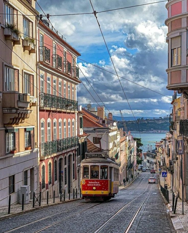 a red trolley car traveling down a street next to tall buildings with balconies