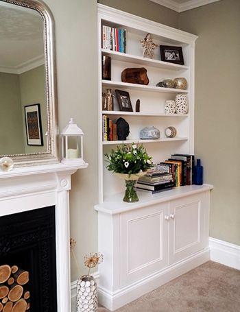 a living room with a fire place and bookshelf next to a mirror on the wall