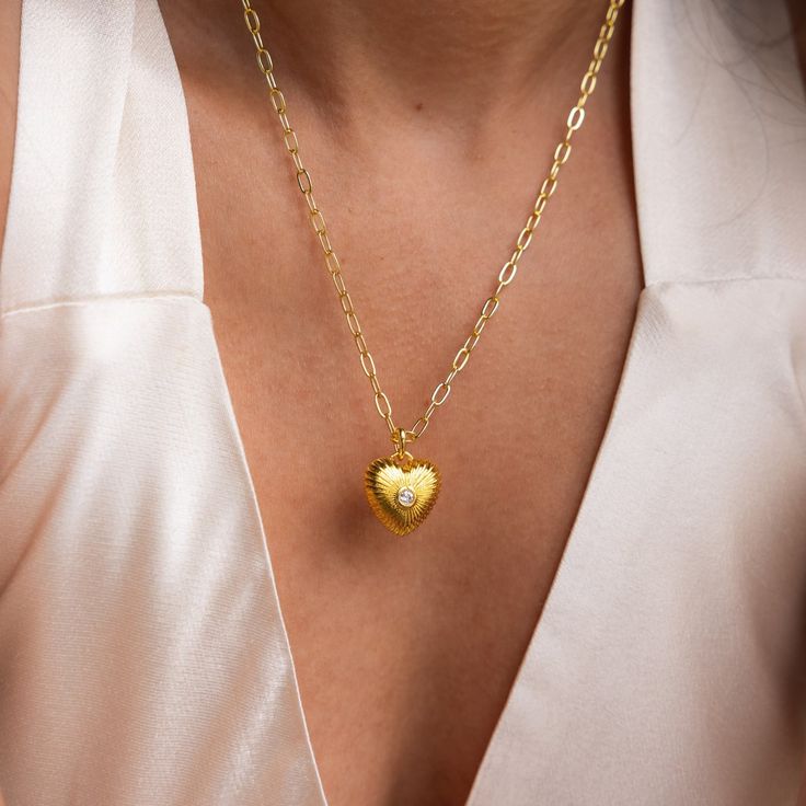 Get ready to fall in love with our Diamond Ribbed Heart Pendant! With its vintage-inspired design and diamond centerpiece, this pendant embodies charm and allure, making it the perfect accessory to showcase your flirtatious style with a hint of elegance. SKU: RR-NR214 Product Details Finish/Material: 18K Gold Over Brass ∙ Rhodium Over Brass Featuring a ~15x15.5mm Heart Charm with embedded ~3mm Diamond CZ Gemstone on a Paper Clip Chain, adjustable from 16 to 18 inches Featured Styles Part of our Diamond Centerpiece, Vintage Inspired Design, Chain Link Necklace, Snake Chain, Solid 925 Sterling Silver, Heart Charm, Heart Necklace, Heart Pendant, Fall In Love