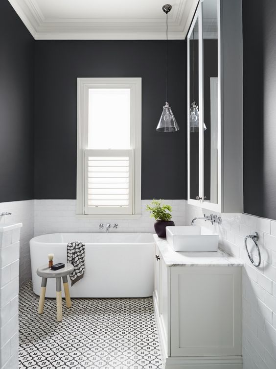 a white bath tub sitting under a bathroom window next to a sink and shower stall