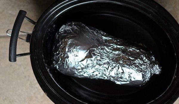 a piece of foil wrapped in aluminum foil sitting inside an open black pot on the ground